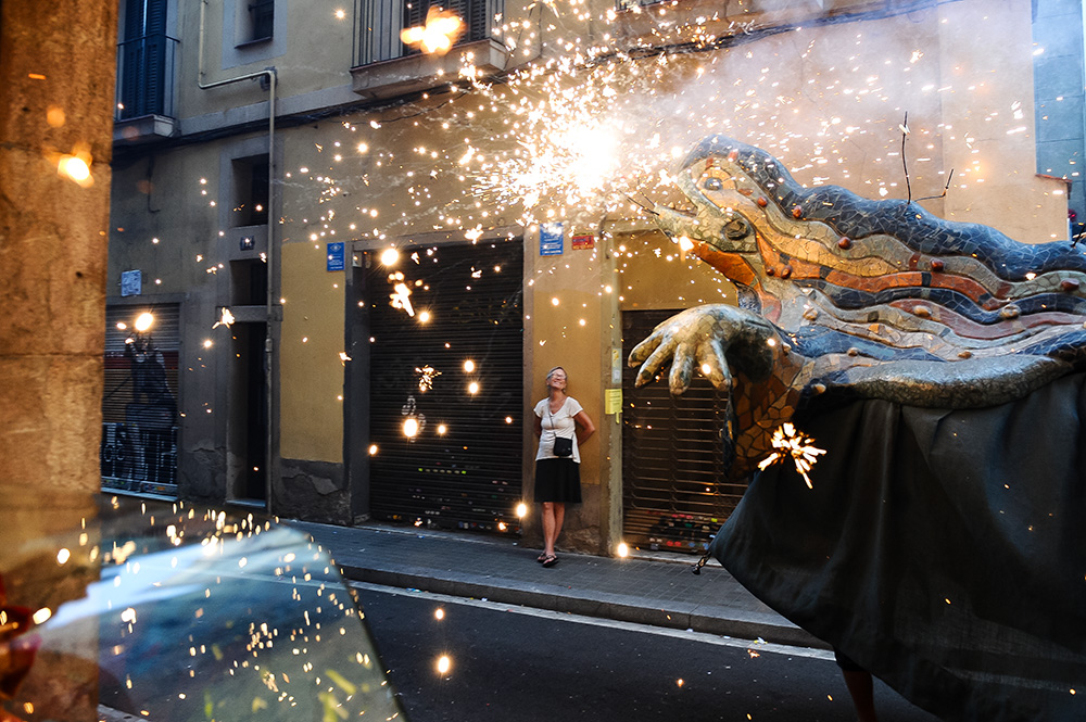 An elderly woman enjoys correfocs fireworks festivity held in Gracia's Barcelona suburb